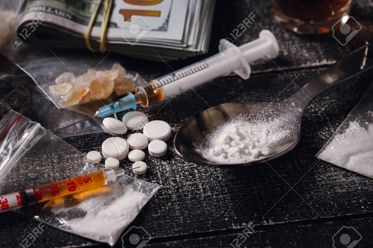 Hard drugs on dark table. Drug syringe and cooked heroin